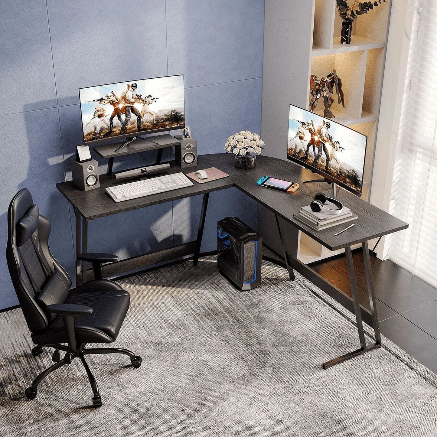 Modern gaming setup with L-shaped black desk, dual monitors, black ergonomic chair, and PC tower