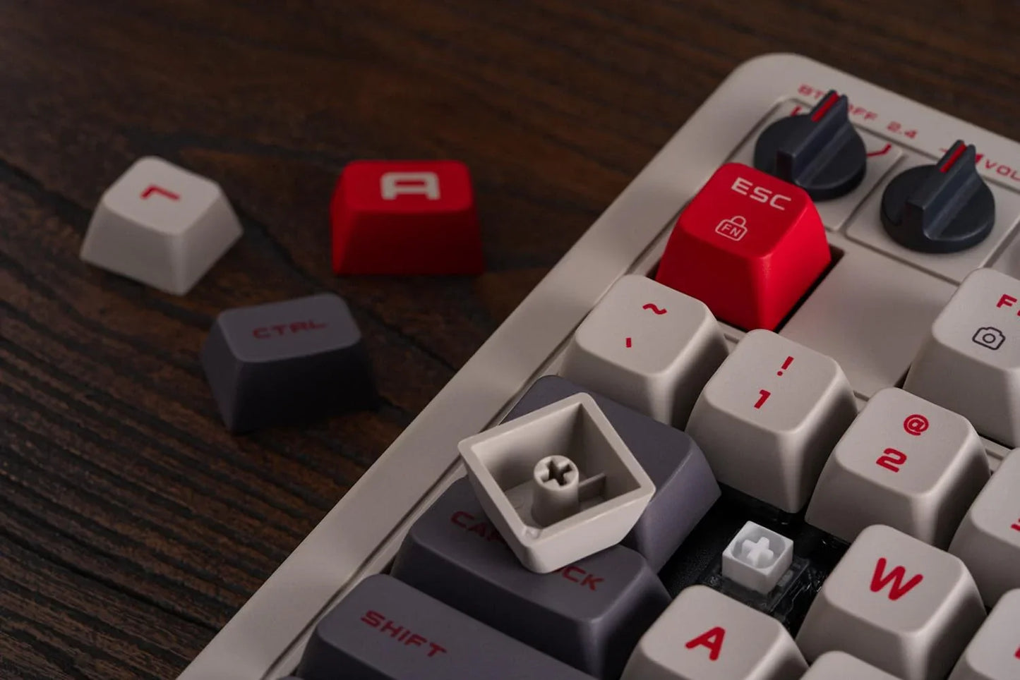 Close-up of retro gaming mechanical keyboard with red and gray keycaps on wooden desk