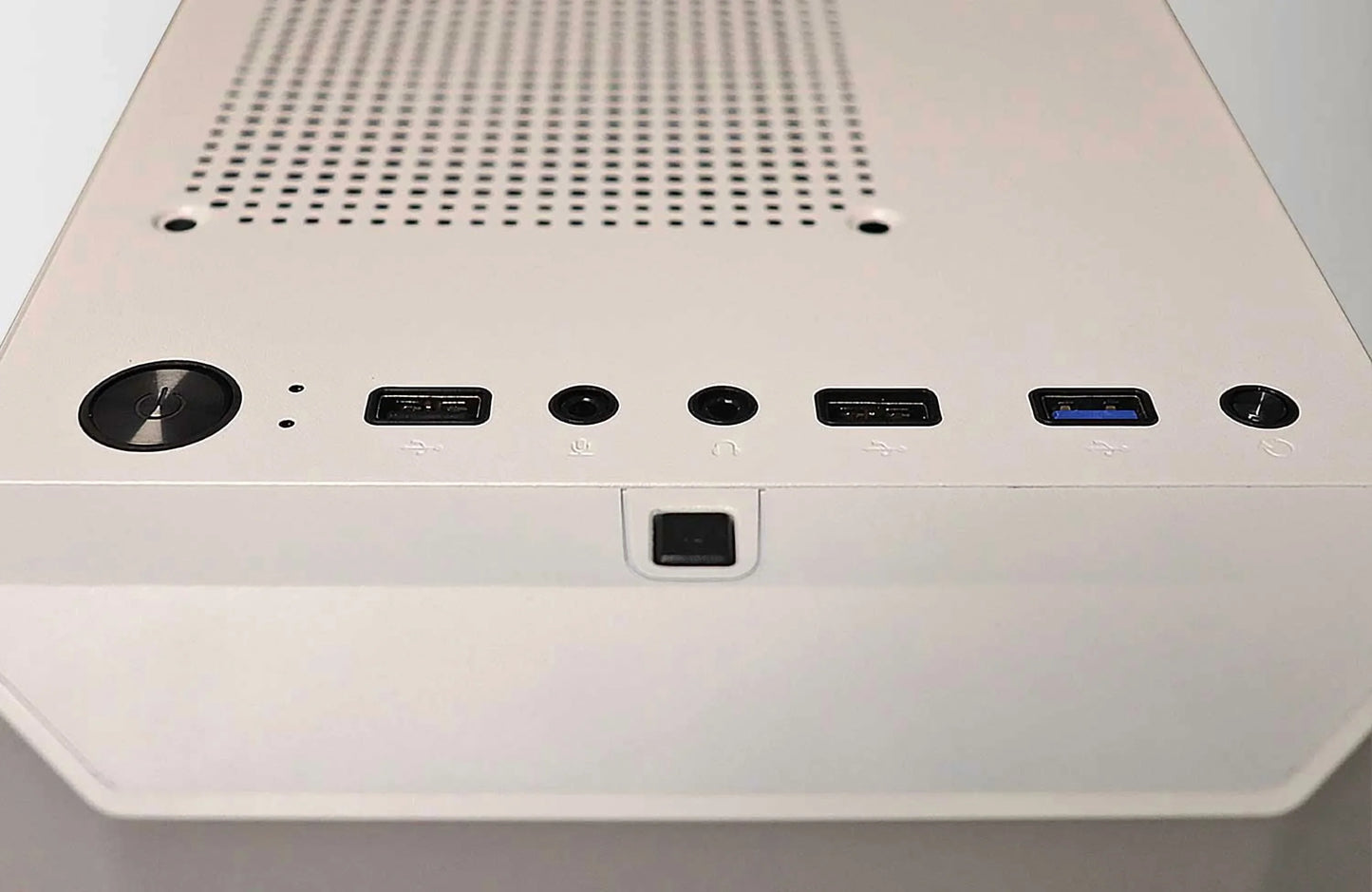 Close-up of white PC case top panel with power button, USB ports, headphone and microphone jacks