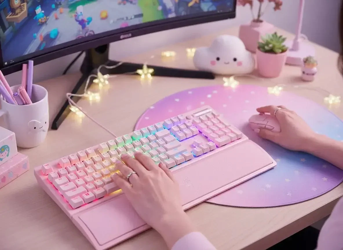 Pastel pink gaming setup with RGB keyboard, mouse, cute decor, and curved monitor