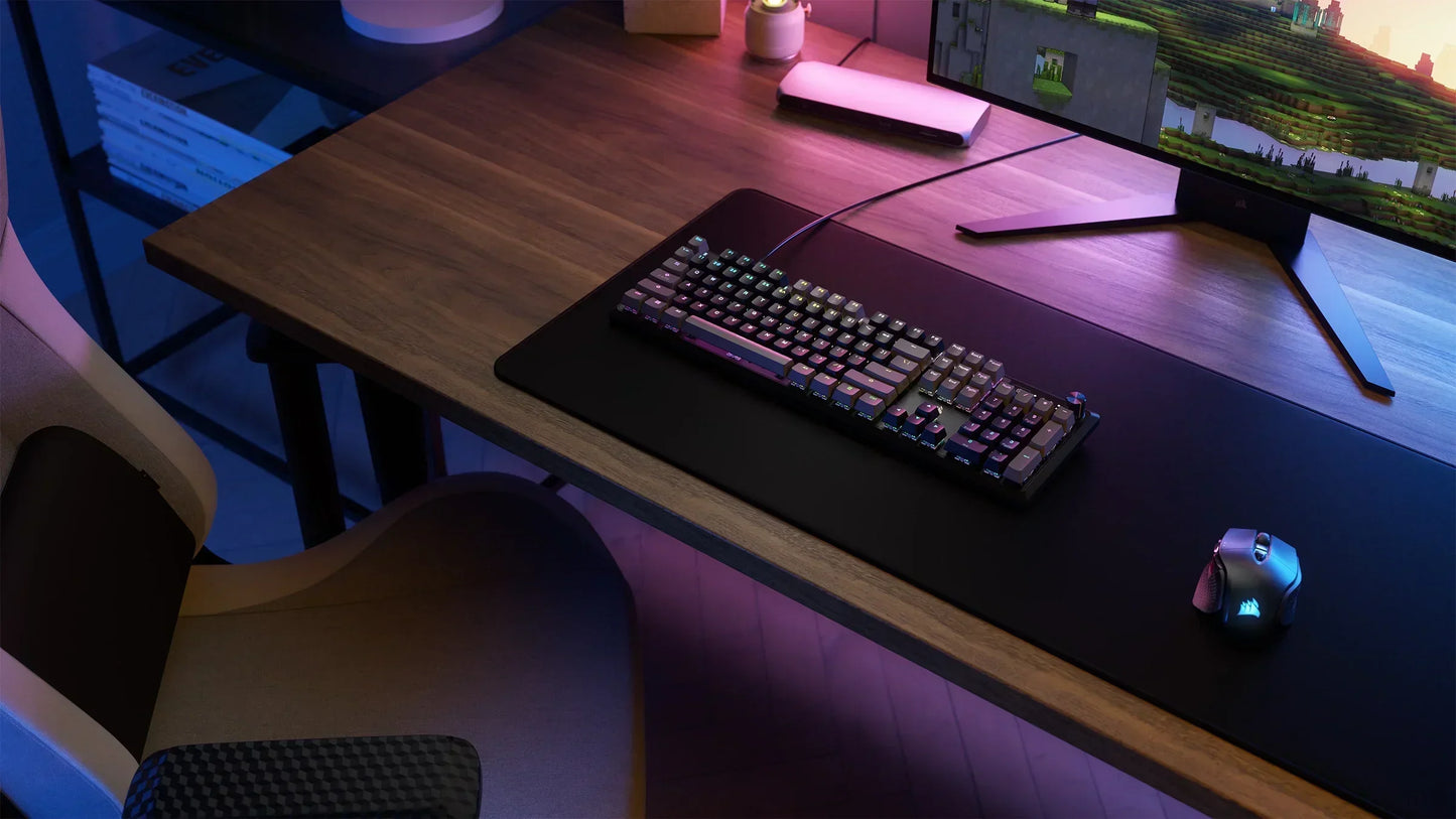 RGB gaming keyboard and mouse on a desk with ergonomic chair, large monitor, modern setup