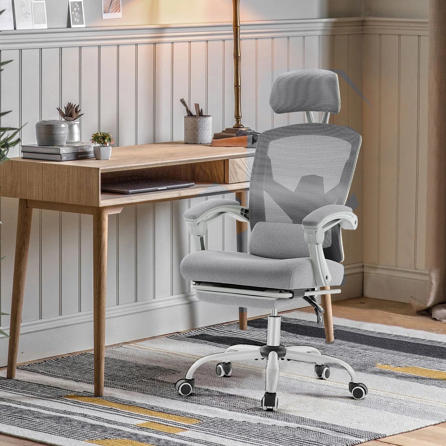 Gray ergonomic mesh office chair with headrest and lumbar support at modern desk setup
