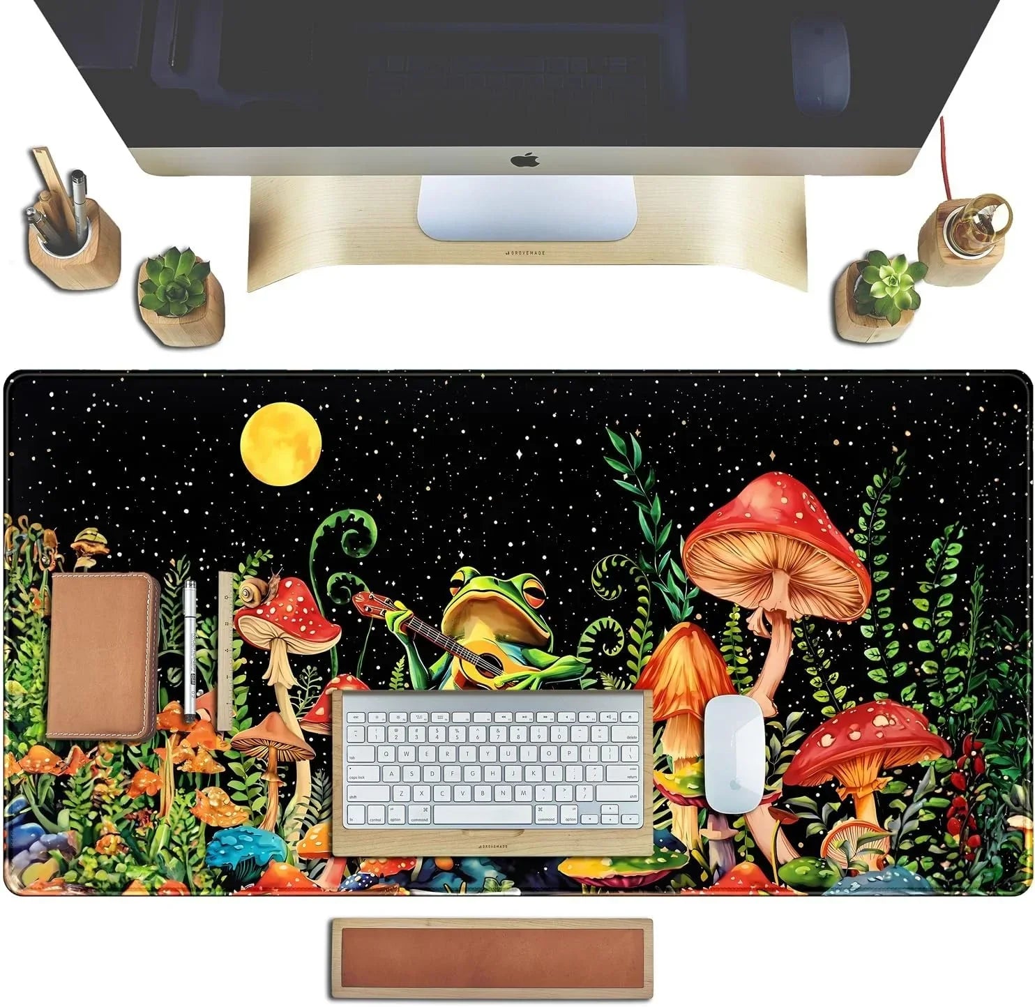 Desk setup with colorful mushroom and frog guitar art mousepad, keyboard, mouse, plants, and wooden accessories