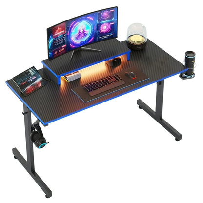 Black and blue carbon fiber gaming desk with curved monitor, RGB keyboard, mouse, headphones, and cup holder