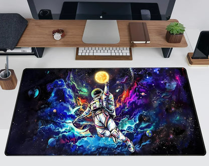 Desk setup with a colorful space-themed gaming mouse pad featuring an astronaut reaching for a glowing sun among planets