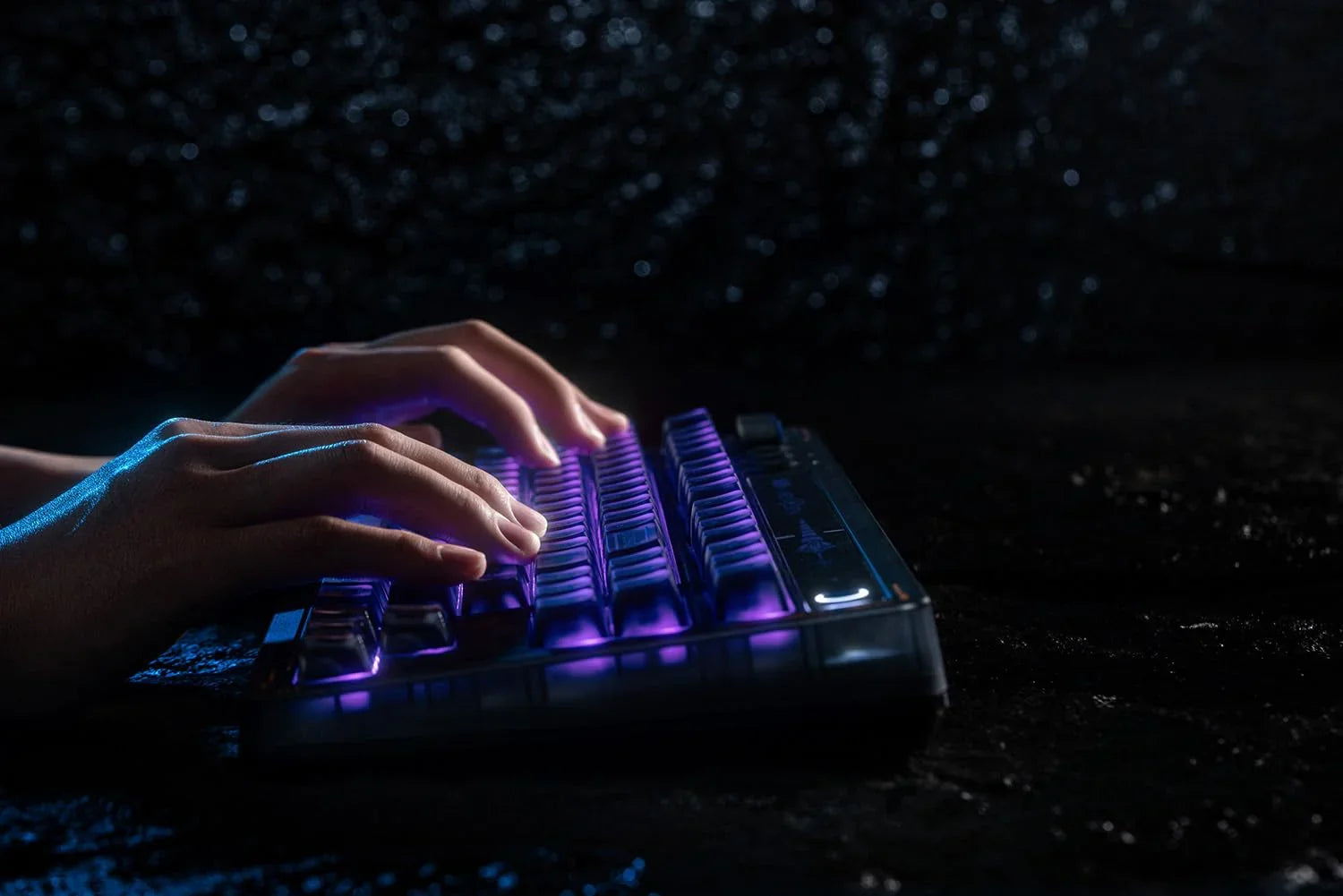 Hands typing on a backlit mechanical gaming keyboard with purple LED lights