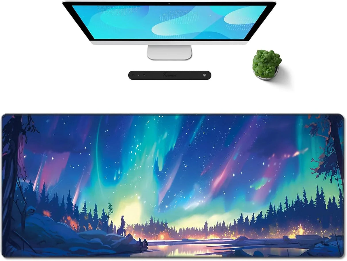 Large gaming desk mouse pad with glowing northern lights and forest landscape design under computer and plant