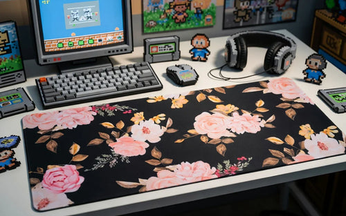 Floral gaming desk mat with pink roses on a desk, retro keyboard, mouse, and pixel art decor