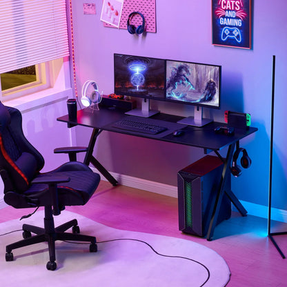Modern gaming setup with dual monitors, gaming PC, black desk, ergonomic chair, colorful LED lighting