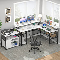 Modern L-shaped white office desk with dual monitors, lamp, tablet, chair, printer cart, and books under large windows