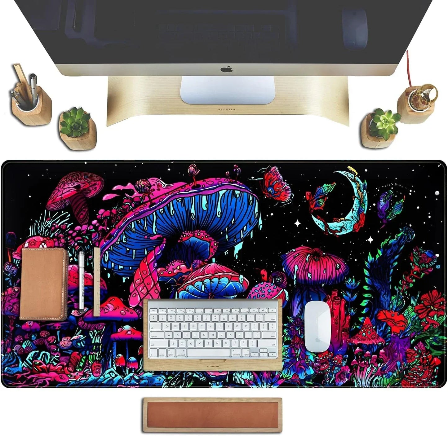 Top view of a desk setup with colorful mushroom-themed extended gaming mouse pad, keyboard, mouse, and wooden desk accessories
