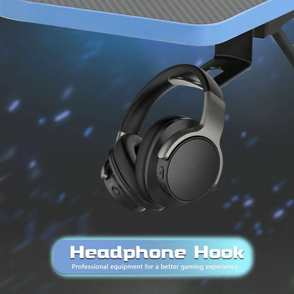Black wireless headphones hanging on a black and blue gaming desk with a headphone hook