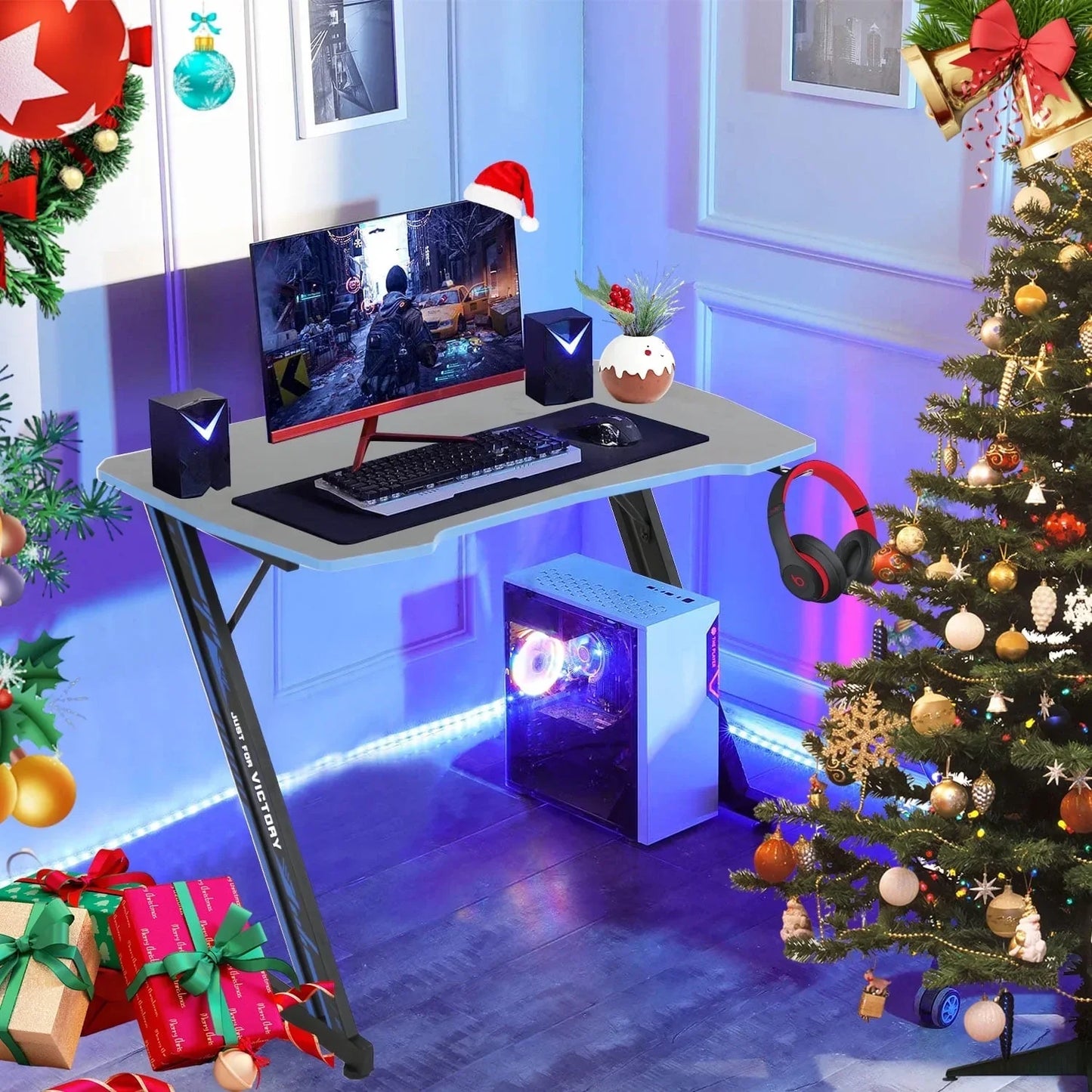 Modern gaming desk setup with curved monitor, PC tower with RGB lighting, speakers, keyboard, mouse, and Christmas decor