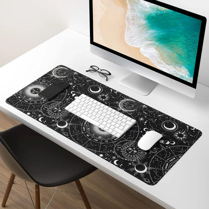 Modern white desk setup with large celestial-themed black mouse pad, wireless keyboard and mouse, computer monitor, smartphone, and glasses