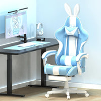 Light blue and white gaming chair with bunny ears next to black desk with white keyboard, mouse, and headphones