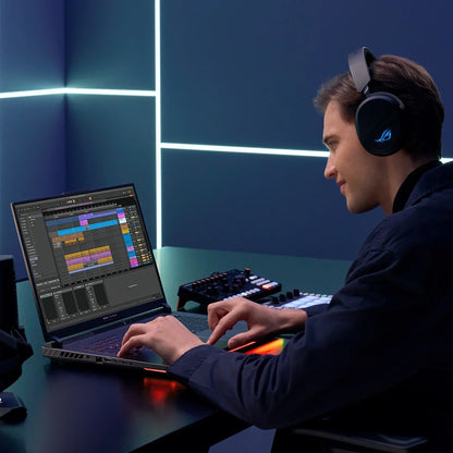 Man using gaming headphones and RGB laptop for music production in modern studio