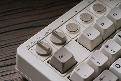 Retro mechanical keyboard with control knobs on wood desk, featuring F1, F2 keys and Esc key.