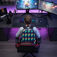 Child gaming at a dual monitor setup with RGB keyboard and mouse, sitting in a black and red gaming chair with colorful backpack
