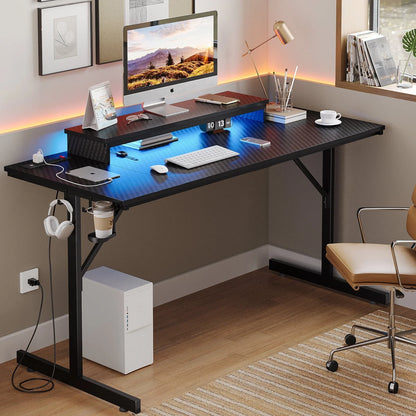 Modern home office setup with black carbon fiber desk, desktop computer, wireless keyboard, mouse, and ambient lighting