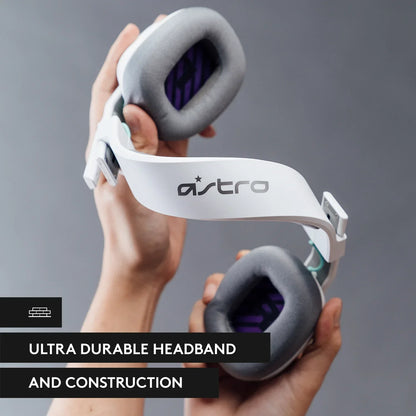 Hands holding white Astro gaming headphones with gray cushions against gray background