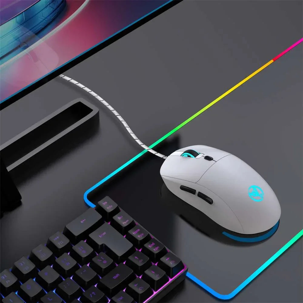 White wired gaming mouse with RGB lighting on colorful RGB mousepad next to black mechanical keyboard