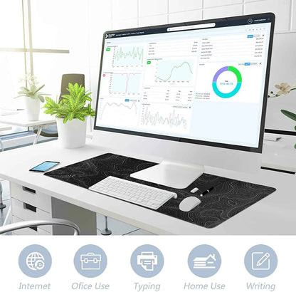 Modern workspace with large monitor displaying data graphs, white keyboard and mouse on black patterned desk mat, potted plants nearby