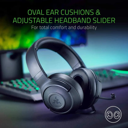 Black gaming headset with oval ear cushions and adjustable headband on desk with keyboard