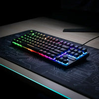 RGB backlit mechanical gaming keyboard on black circuit-patterned desk mat in a dim room