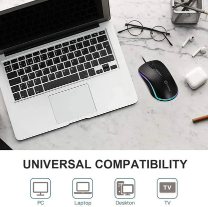 Wired RGB gaming mouse beside laptop on marble desk, showing universal compatibility.