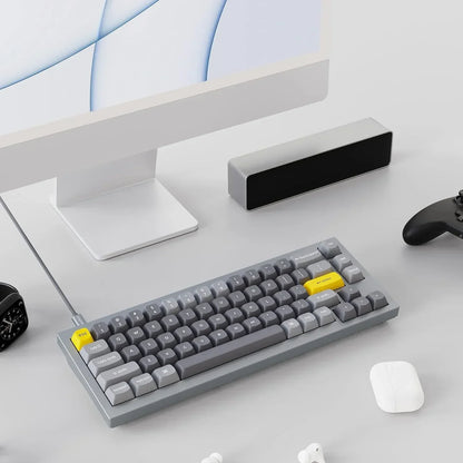 Modern gaming setup with gray mechanical keyboard, yellow keycaps, monitor, controller, and desk accessories