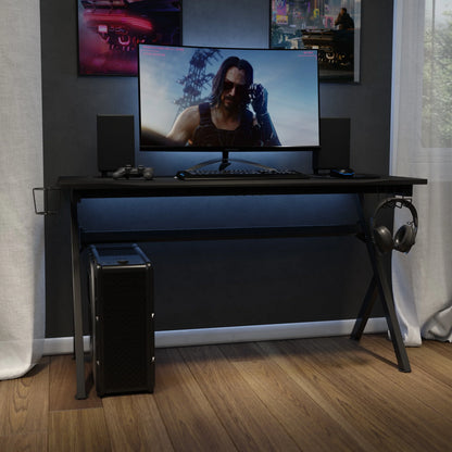 Modern black gaming desk setup with ultrawide monitor showing cyberpunk character, keyboard, mouse, speakers, and PC tower