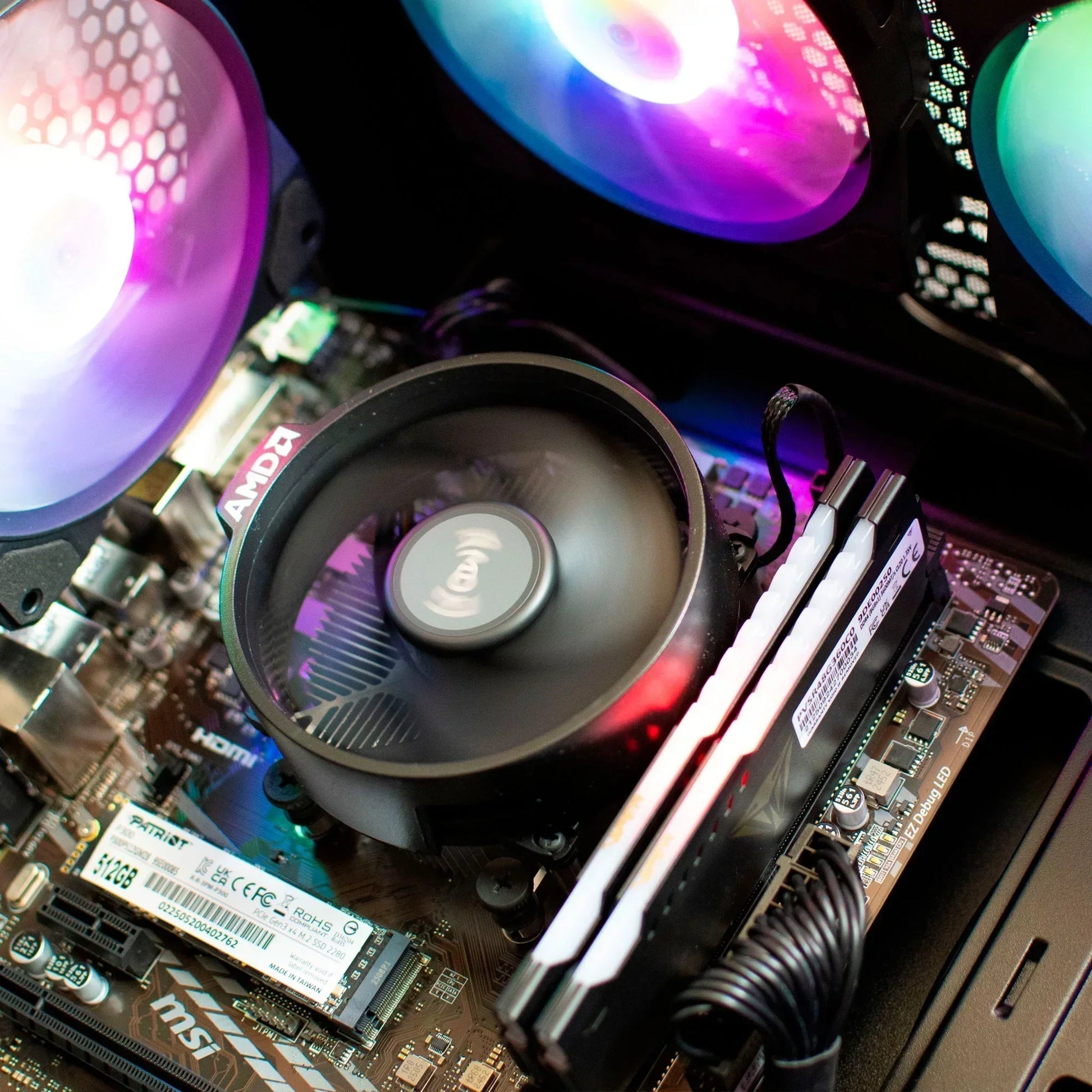 Close-up of a gaming PC motherboard with AMD CPU cooler, RGB fans, RAM, and SSD installed