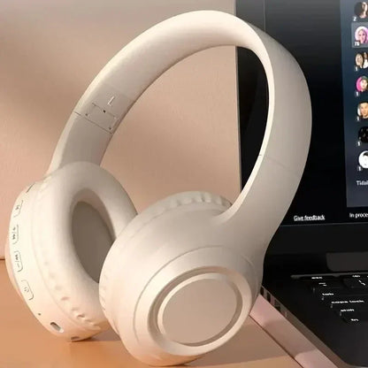 White wireless gaming headset resting beside a laptop, ideal for PC gamers and streaming.