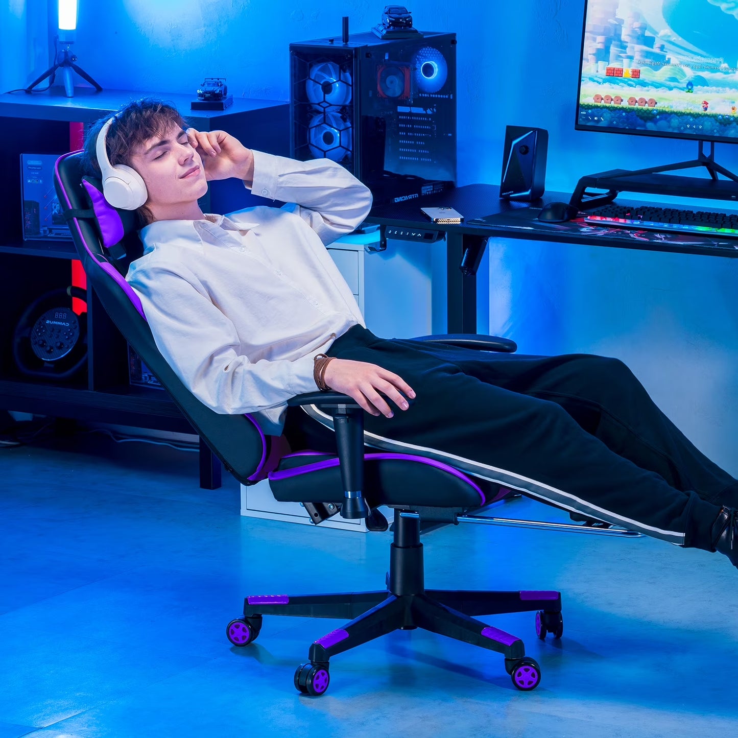 Gamer relaxing in purple-accented gaming chair with RGB keyboard, PC, and headset in blue-lit setup
