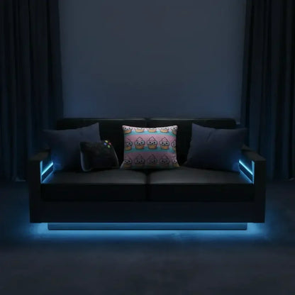 Black modern sofa with three decorative pillows and blue LED accent lighting in a dark room