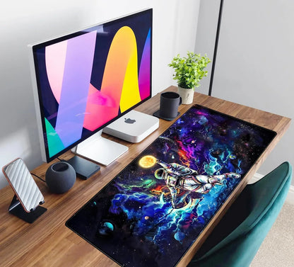 Modern wooden desk setup with colorful astronaut galaxy gaming mouse pad, monitor, Mac mini, plant, and black mug