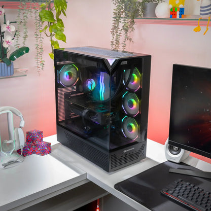 Gaming PC with RGB cooling fans on a white desk next to a monitor and white headphones