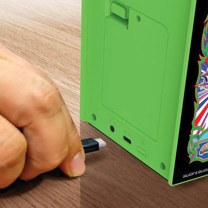 Hand plugging USB cable into green retro arcade gaming device on wood desk