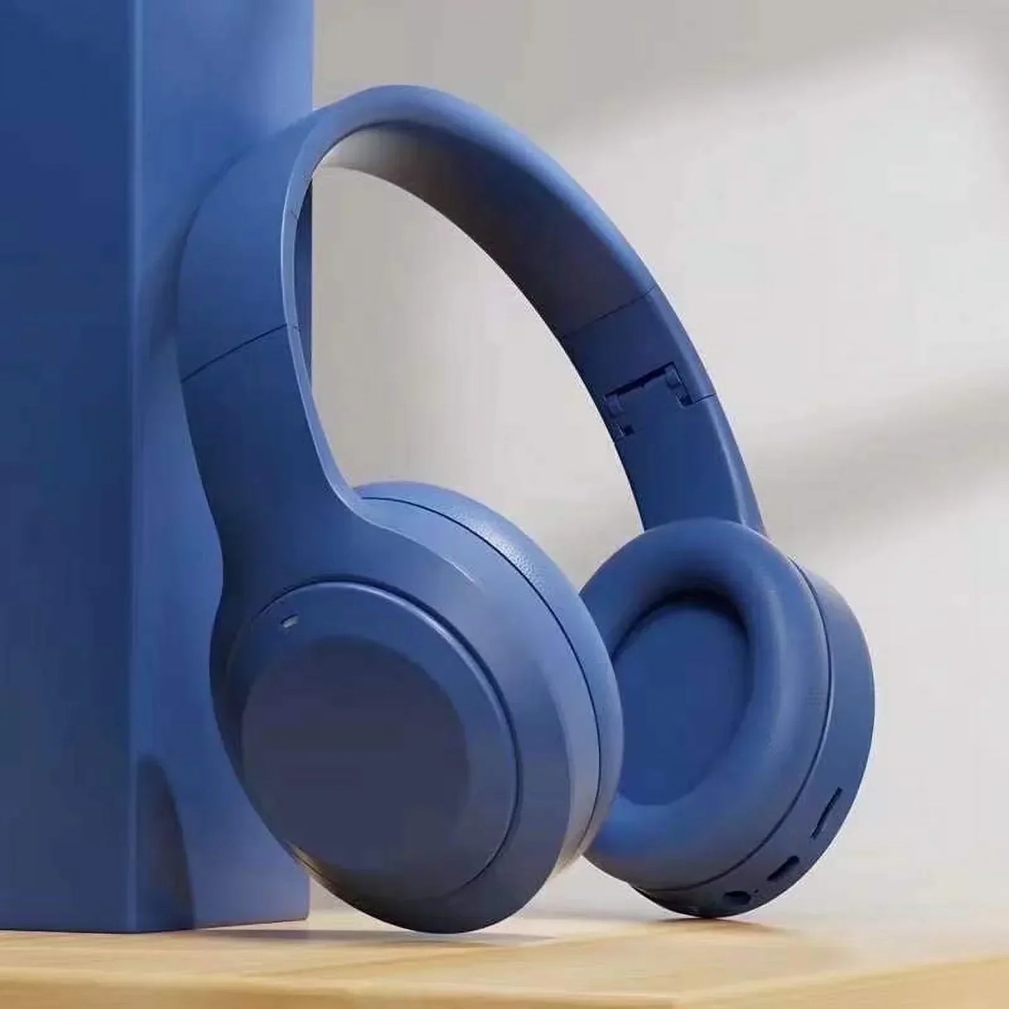 Blue over-ear wireless gaming headset on a wooden surface, minimalist background