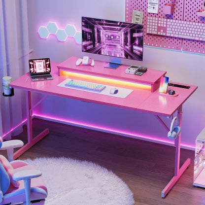 Pink gaming desk with RGB lighting, monitor, keyboard, mouse, laptop, and gaming accessories in modern setup