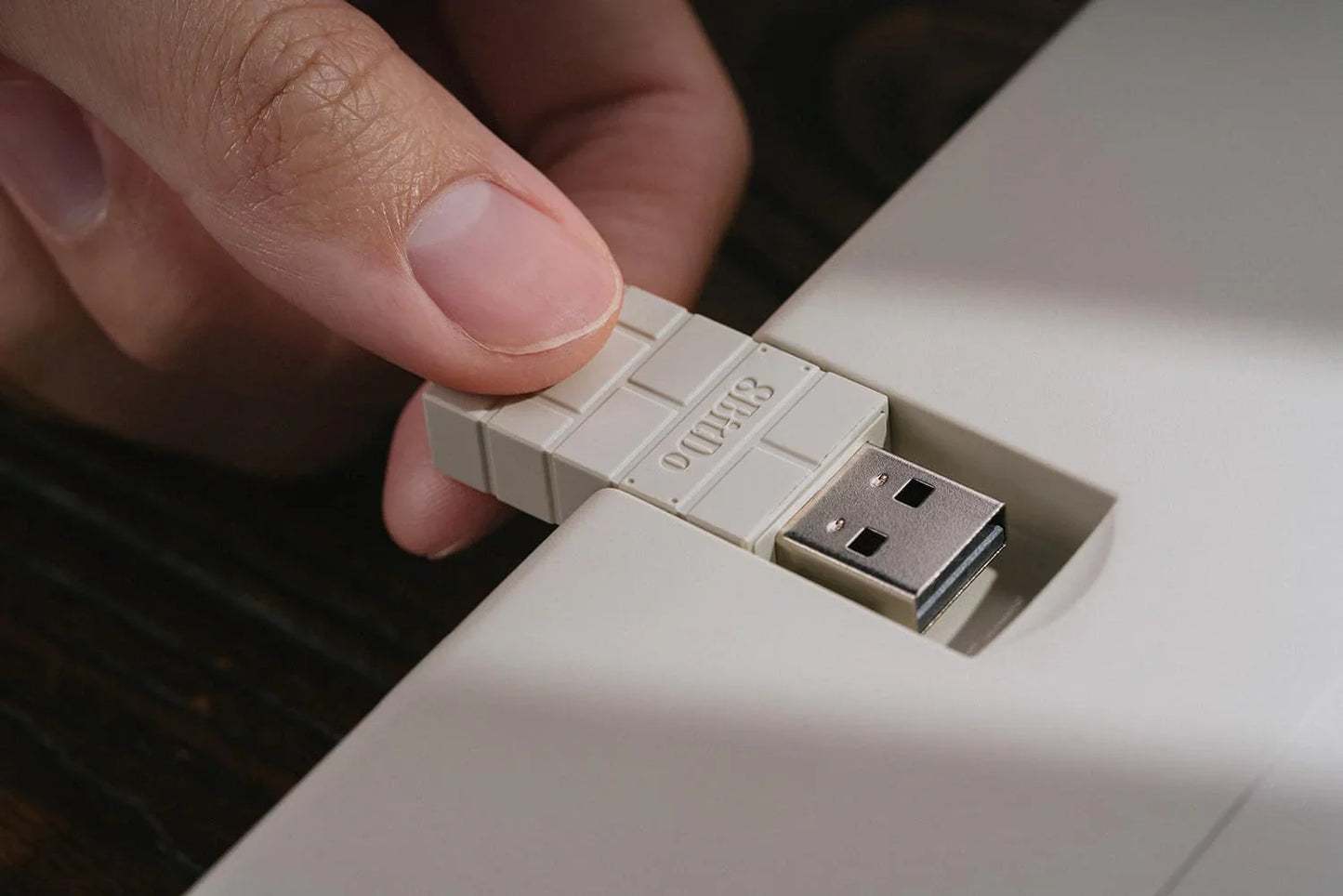 Hand plugging retro-style USB stick into keyboard for gaming setup