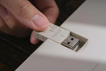 Hand plugging retro-style USB stick into keyboard for gaming setup