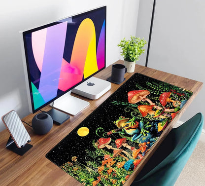 Modern desk setup with Mac monitor, compact Mac Mini, black mushroom frog gaming desk mat, plant, and teal chair