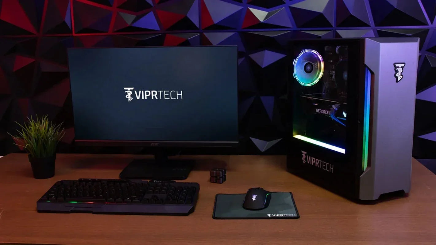 VIPRTECH gaming desktop setup with RGB-lit PC tower, monitor, keyboard, mouse on desk with geometric wall background