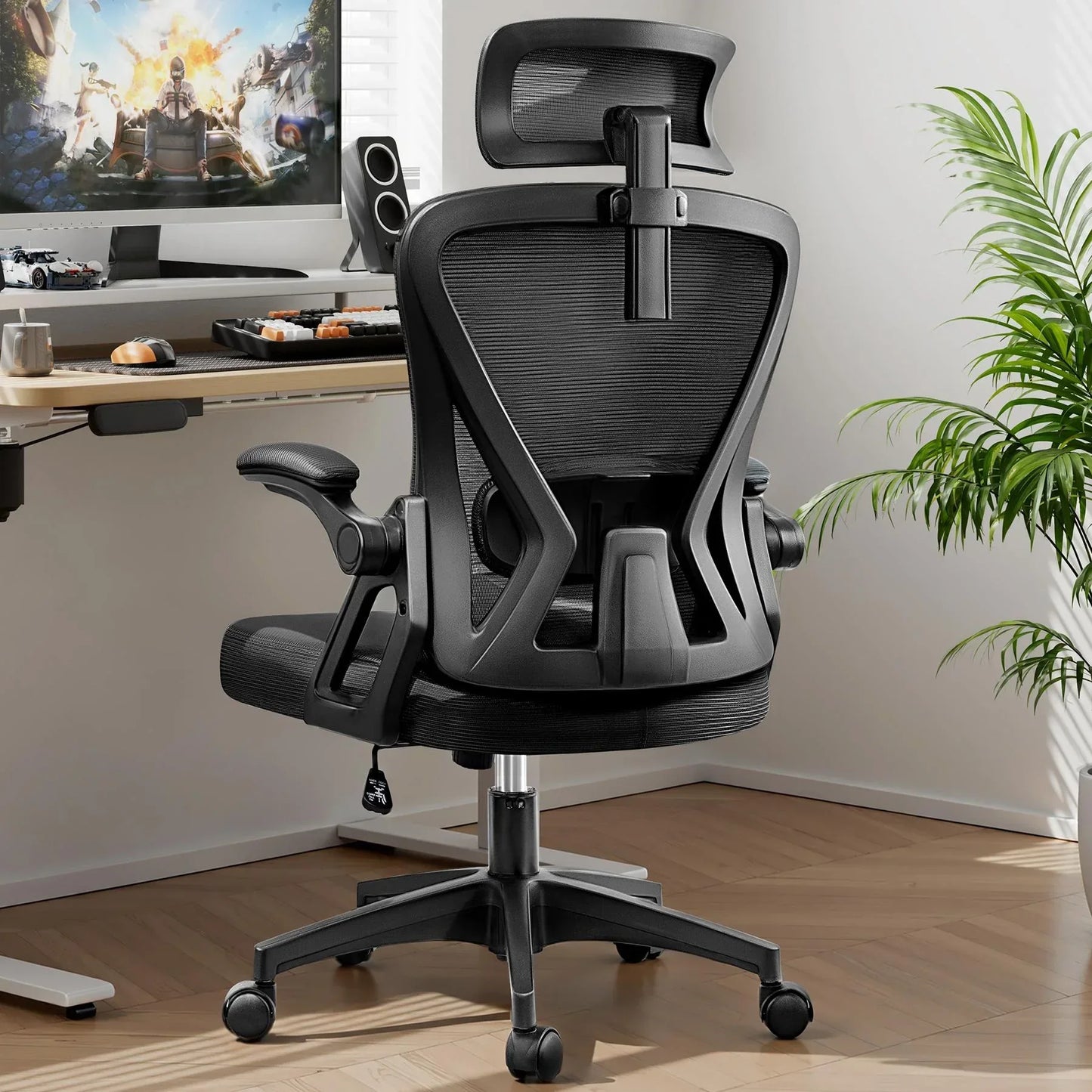 Black ergonomic gaming chair with mesh back, headrest, and armrests at a desk setup with monitor and keyboard