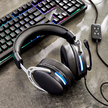 Black gaming headset with blue LED lights next to RGB mechanical keyboard on gray surface