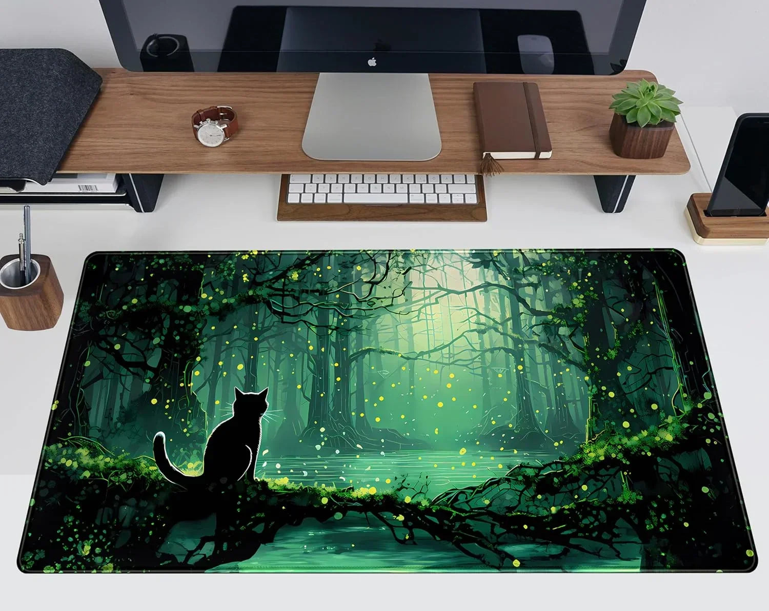 Gaming desk setup with large mouse pad featuring glowing forest scene and black cat silhouette