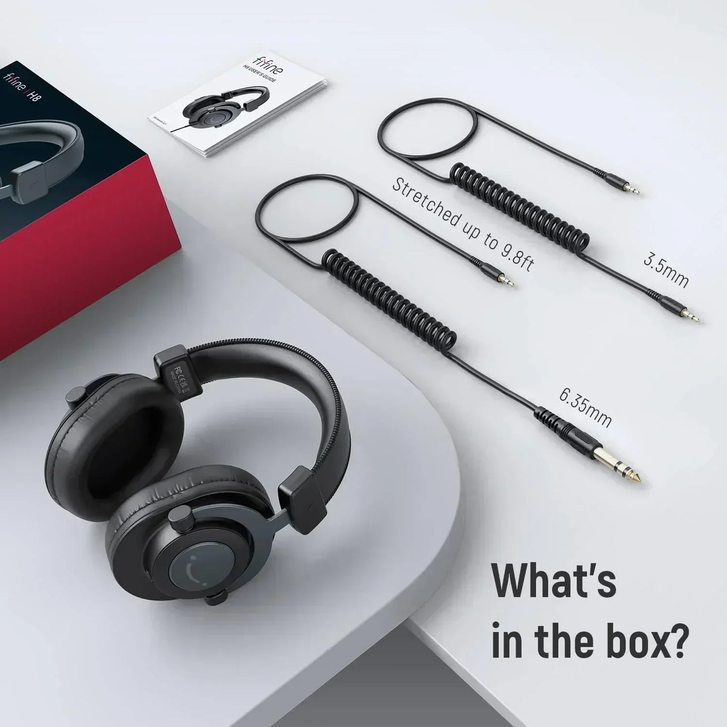 Gaming headset with coiled audio cables, 3.5mm and 6.35mm adapters, and user manual on a desk.