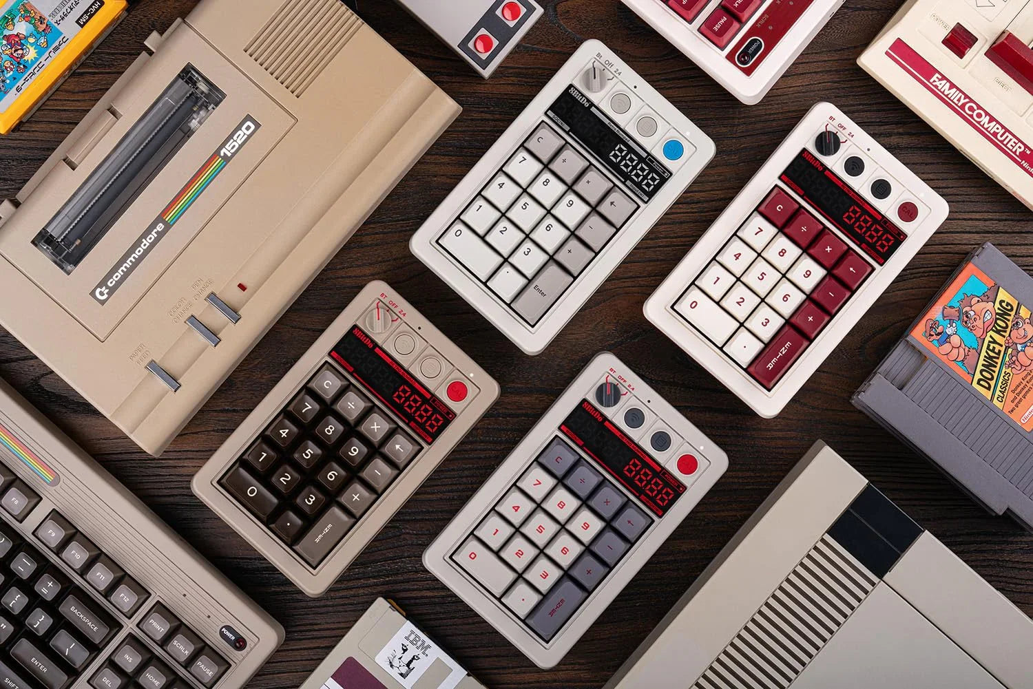Retro gaming gear and classic computers with 8-bit style number pads on wood surface.