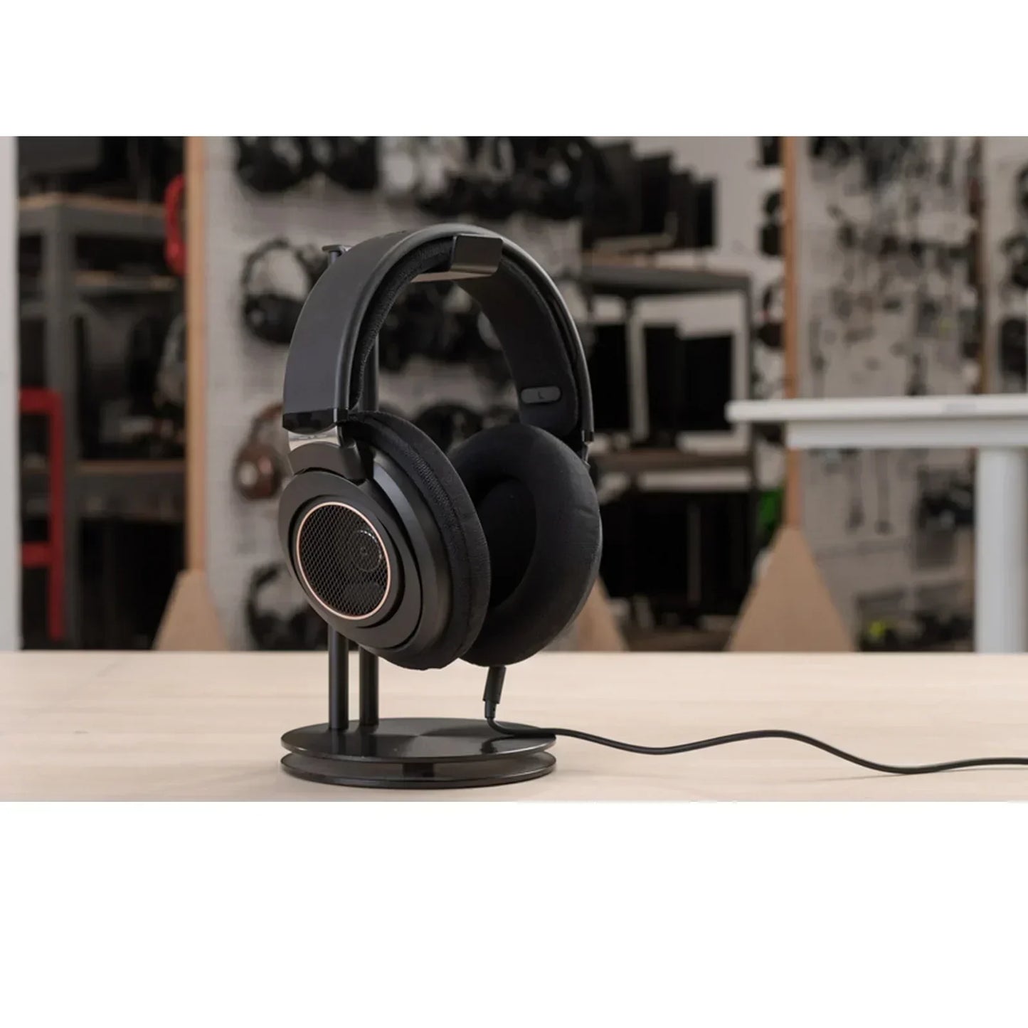 Black wired gaming headset on a stand, displayed on a desk in a tech workspace.